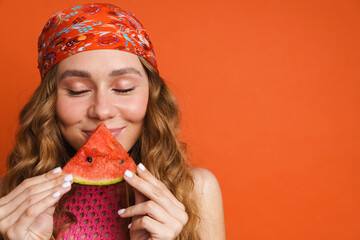Young ginger woman in bandana smiling while eating water melon