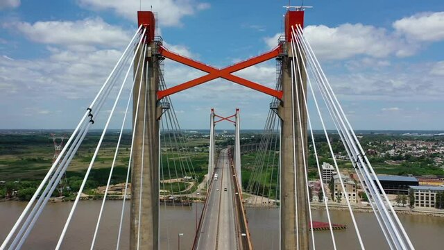 Drone flying backwards revealing the amazing huge bridge of Zarate where vehicles are crossing it, Argentina.