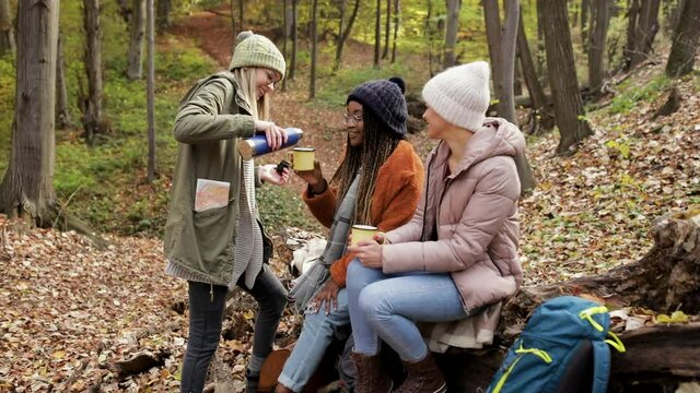 Three female friends having fun and enjoying hiking in forest.