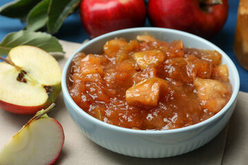Tasty apple jam in bowl and fresh fruits on table, closeup