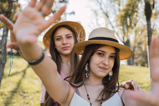 Smiling girlfriends in straw hats spending time in park