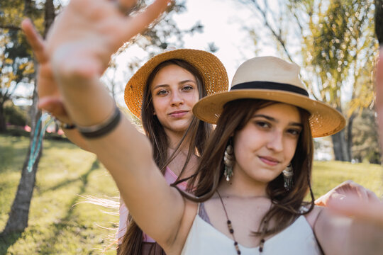 Smiling girlfriends in straw hats spending time in park