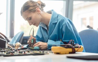 Worker in electronics manufacturing soldering a component for the prototype series by hand