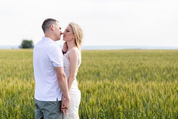 young couple kissing in the field. Asian woman hugs Caucasian man in the middle of wheat field and kisses each other. concept about passion and love