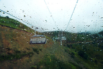 Large raindrops on the glass are in focus, the window, the cable car, several funiculars are blurred, out of focus. rainy weather. the concept of sadness. advertising of tourist services