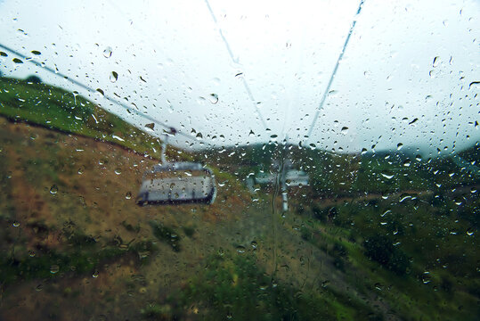 Large raindrops on the glass are in focus, the window, the cable car, several funiculars are blurred, out of focus. rainy weather. the concept of sadness. advertising of tourist services - Powered by Adobe