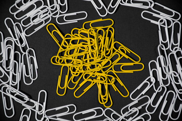 Yellow paperclip isolated in the frame made of white paperclip. paperclip on black background