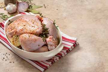 Whole raw chicken with herbs and spices ingredients in a baking dish. Cooking chicken in the oven. Tasty homemade food.  Copy space for text