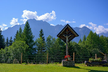 wayside cross on an alp above Lienz with dolomites in the background, Austria