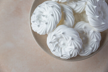 Plate with empty meringue nests, light stone background. Concept for a tasty sweet dessert.