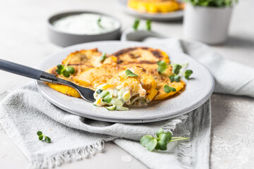 Fried patisson or yellow zucchini with sauce and micro greens, grey concrete background.
