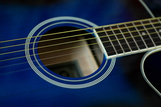 Wooden blue classical guitar with strings and sound hole visible