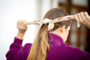 the girl's hands are tying a scarf