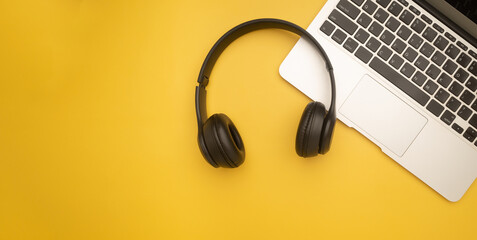 Top view of a headphones over on a laptop isolated on a yellow background with space for text