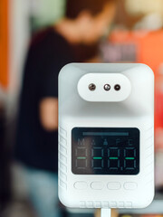 Obraz premium Digital automatic body measuring temperature machine for measuring body temperature by placing a hand over the sensor in a coffee shop for mandatory checks of customers during the Covid-19 pandemic.