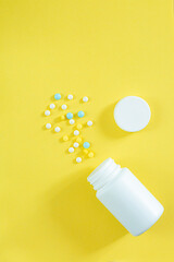 pills and pill bottles on yellow background,Medical pills scattered from a white tube on a yellow background. Open mock-up Birth control pills.