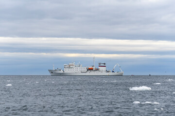 Expedition ship in Arctic sea with ice. White research vessel.