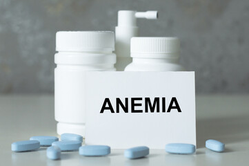 a white card with anemia wrant on the table next to the cans of medicines and scattered blue pills