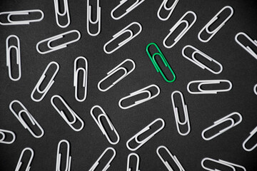 Green paper clip inovative idea concept on black background. stand out of the crowd