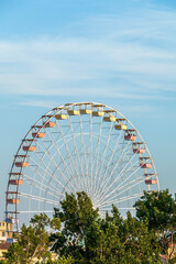 Fototapeta premium Ferris wheel in the amusement park as tourist attraction on the background of blue sky with copy space