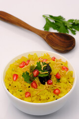 Indian breakfast Poha garnished with pomegranate seeds, chopped green chilly, coriander leaves and curry leaves.