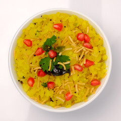 Indian breakfast Poha garnished with pomegranate seeds, chopped green chilly, coriander leaves and curry leaves.