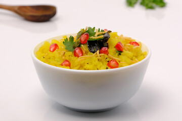 Indian breakfast Poha garnished with pomegranate seeds, chopped green chilly, coriander leaves and curry leaves.