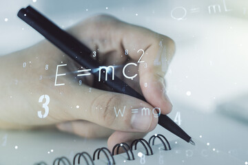 Creative scientific formula concept with man hand writing in notebook on background. Multiexposure