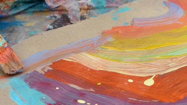 A little girl draws with a brush and paints. Close-up