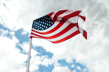 USA America flag waving in the wind over cloudy sky.