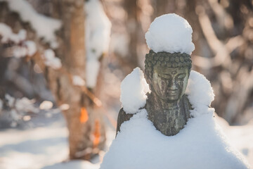 A decorative outdoor garden Buddha statue covered with fresh snow on a winter day in Nelson,...