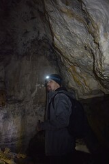 Male hiker exploring a dark cave.Travel destination in Slovakia