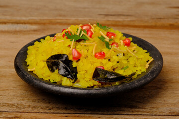 Indian breakfast Poha garnished with pomegranate seeds, chopped green chilly, coriander leaves and curry leaves.