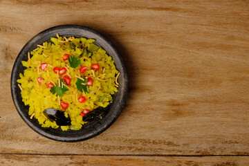 Indian breakfast Poha garnished with pomegranate seeds, chopped green chilly, coriander leaves and curry leaves.