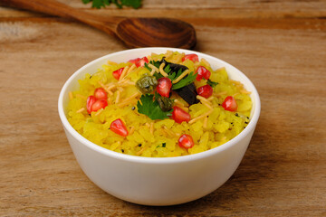 Indian breakfast Poha garnished with pomegranate seeds, chopped green chilly, coriander leaves and curry leaves.