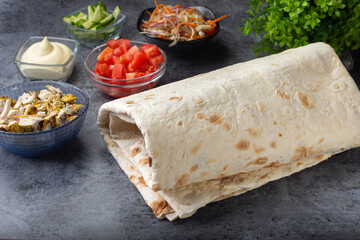 Pita bread sheets wrapped in a roll.Lavash. Pita bread sheets on a dark background with ingredients for shawarma. Shawarma with chicken
