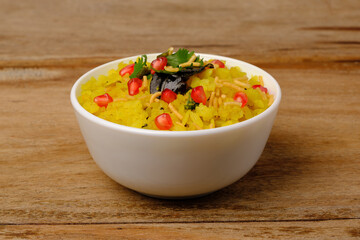 Indian breakfast Poha garnished with pomegranate seeds, chopped green chilly, coriander leaves and curry leaves.