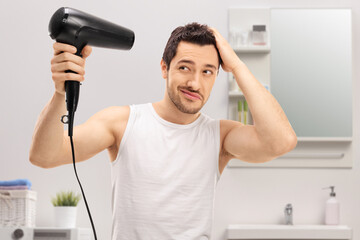 Young man using a hairdryer in a bathroom