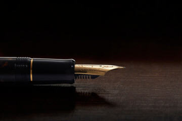 Pena dourada de caneta tinteiro em macro sobre fundo de madeira escura
