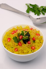 Indian breakfast Poha garnished with pomegranate seeds, chopped green chilly, coriander leaves and curry leaves.