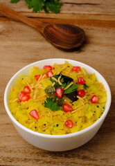 Indian breakfast Poha garnished with pomegranate seeds, chopped green chilly, coriander leaves and curry leaves.