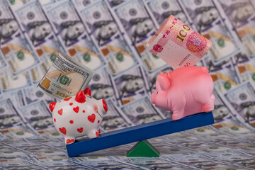 A piggy bank with a 100 American dollar bill outweighs a piggy bank with a 100 Chinese yuan bill on a balancing board