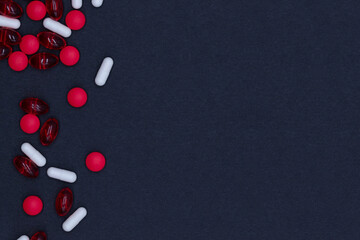 Pharmacy, pharmaceutical industry and healthcare, top view of red and white vitamins, pills and capsules medicines on dark black background, flat lay with blank space