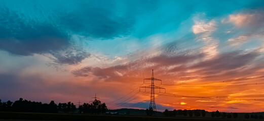 Fototapeta na wymiar Beautiful sunset with a dramatic sky and overland high voltage lines near Eichendorf, Bavaria, Germany