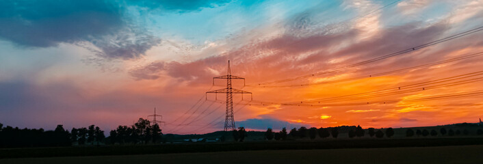 Obraz premium Beautiful sunset with a dramatic sky and overland high voltage lines near Eichendorf, Bavaria, Germany