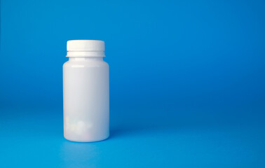 White bottle of pills on blue background