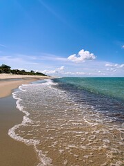 Wild white sand beach, empty beach, sea coastline, blue sky, azure water surface 