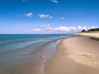 Wild white sand beach, empty beach, sea coastline, blue sky, azure water surface 