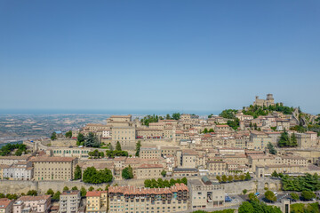 Fototapeta na wymiar Aerial view of San Marino old town with old buildings and red roofs on the hill on a sunny day with clear sky
