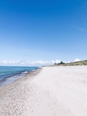 Wild white sand beach, empty beach, sea coastline, blue sky, azure water surface